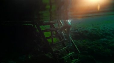 Güzel kız merdivenlerden tırmanıyor ve şeffaf gölden geliyor