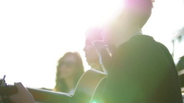 Eğlenceli ve bir gitar ile şarkıları söyleyerek yaz parkta günbatımında sahip genç Beyaz arkadaşlar