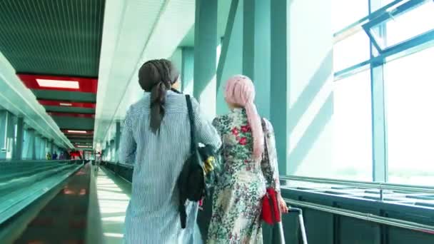 Duas meninas muçulmanas caminhando pelas janelas do aeroporto — Vídeo de Stock