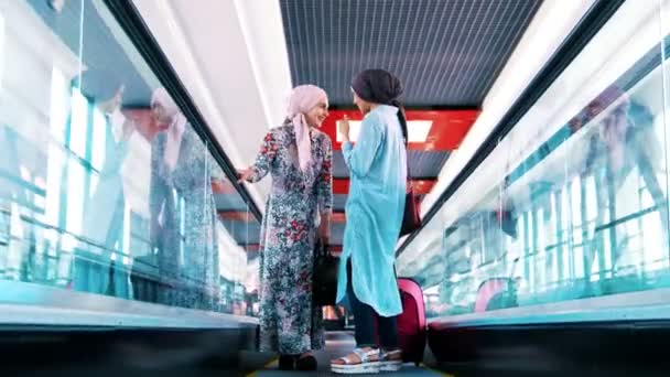 年轻的穆斯林女孩坐自动扶梯, 说话和笑 — 图库视频影像