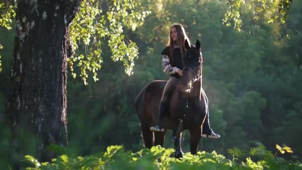Jezdkyně na sobě žokeje na pozadí zeleného lesa, brzy ráno, získá ze svého koně — Stock video