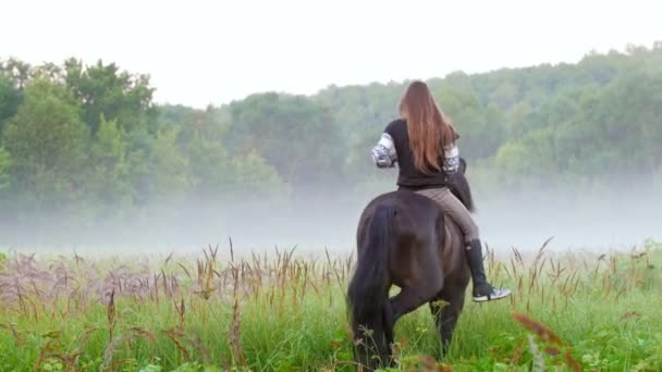 Las niñas a caballo se mueven a la niebla temprano en la mañana — Vídeos de Stock