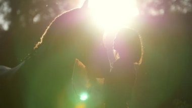 Güzel bir kız ve bir at sabah erken keyifli yaz güneş ışınlarının ormanda bir yürüyüşe silüeti