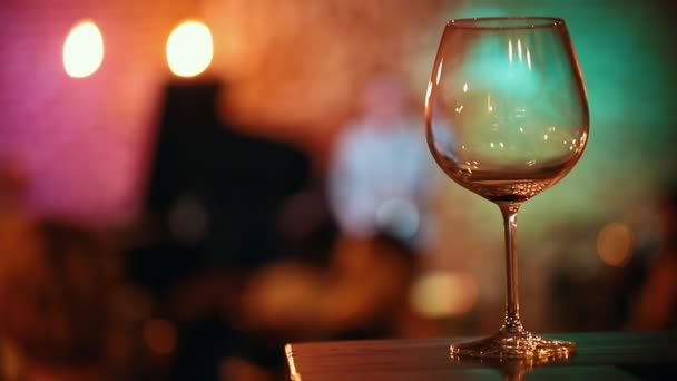 Tomma glas vin står på baren, i bakgrunden musikerna och reflexer från lampor — Stockvideo