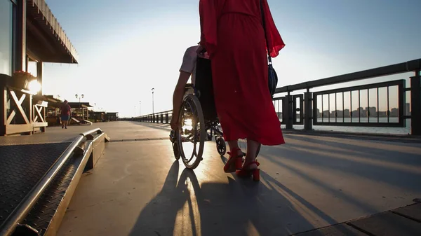 Дівчини з рудим волоссям в Помаранчеве плаття рулонах інвалідів хлопець, який підняв руки в сторони — стокове фото