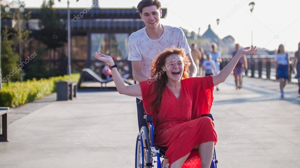 Guy Rolls A Disabled Beautiful Girl In A Wheelchair Outdoors
