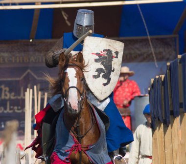 Bulgar, Rusya Federasyonu - Ağustos 2018 -, bir kat arması ile şövalyeler elbiseli bir adam bir ortaçağ festivalinde bir ata biniyor.