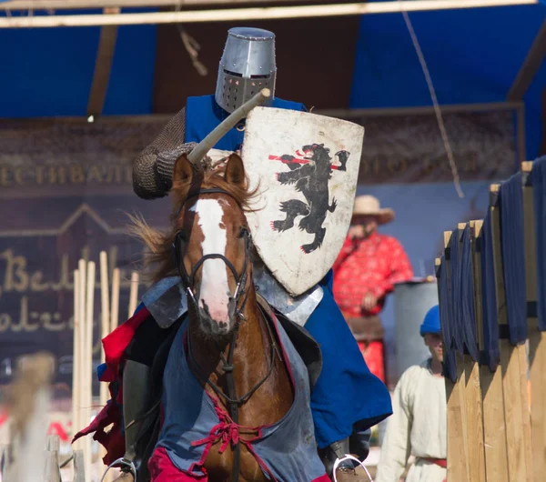 Bulgar, Federación Rusa - Agosto 2018, - un hombre con traje de caballero con escudo de armas monta a caballo en un festival medieval —  Fotos de Stock