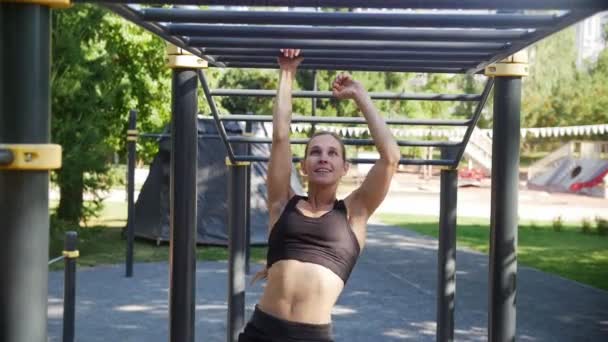 Fiatal sportos lány mutatja be a mozgékonyságot és az erőt a szimulátor a parkban — Stock videók