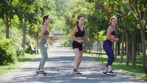 Tre unga kvinnor jogga i parken i sommar — Stockvideo