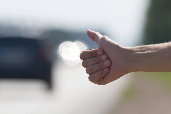 Mano de un hombre que toca la bocina a los coches que pasan, viaje de autostop — Foto de Stock