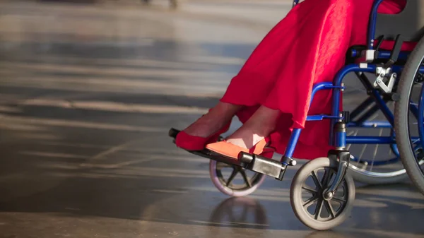 Mädchen im Rollstuhl, im Rahmen weiblicher Beine in roten Schuhen — Stockfoto