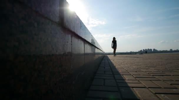 Jeune fille monte une planche à roulettes le long de la clôture en été, la lumière du soleil — Video