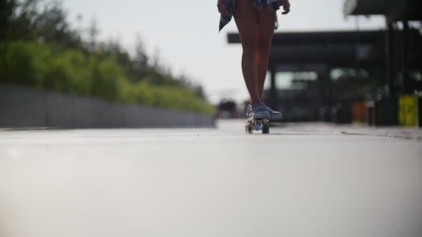 Menina montando um skate no quadro de pernas em tênis — Vídeo de Stock