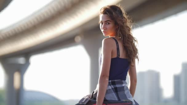 Young beautiful girl with careless curls holds a skate and looks at the camera — Stock Video