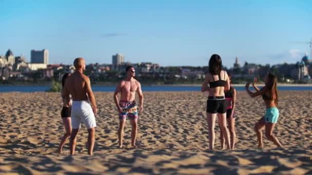 Atletica giovani belle persone che giocano a pallavolo sulla sabbia vicino al fiume — Video Stock