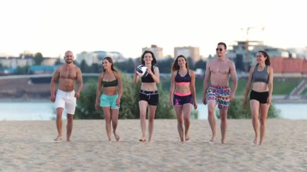 Hermosos jóvenes deportistas caminando por la playa después de un partido de voleibol, hablando, sonriendo, riendo — Vídeos de Stock