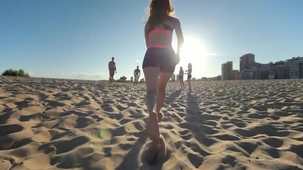 Chica deportiva delgada corriendo en la arena, se detiene y hace la transferencia de pelota a amigos, voleibol de playa — Vídeos de Stock