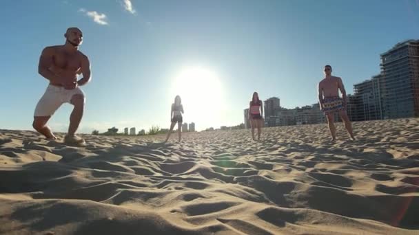 Een man met een sport figuur kale speelt de bal uit met zijn hand en valt op de grond terwijl het spelen van beachvolleybal — Stockvideo