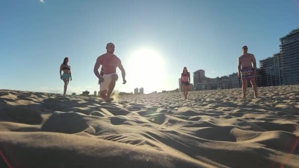 Bonito homem careca com um belo físico bate a bola e cai na areia enquanto joga vôlei de praia — Vídeo de Stock