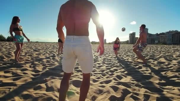 Jovens bonitos esportes pessoas jogam vôlei de praia, o sol brilha brilhantemente — Vídeo de Stock