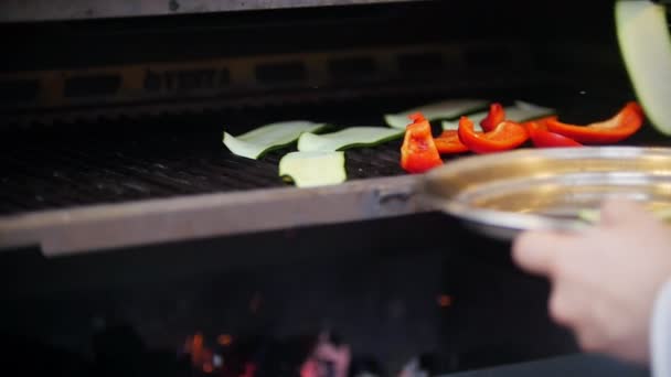 Cook zet gesneden komkommer platen naast stukjes rode paprika in de oven — Stockvideo