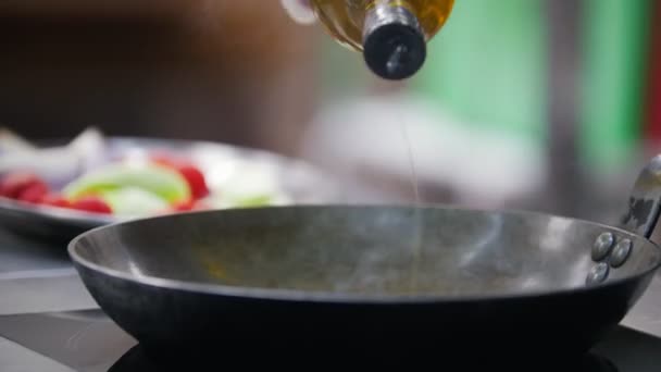 Las manos de los cocineros vierten aceite en una sartén caliente — Vídeo de stock