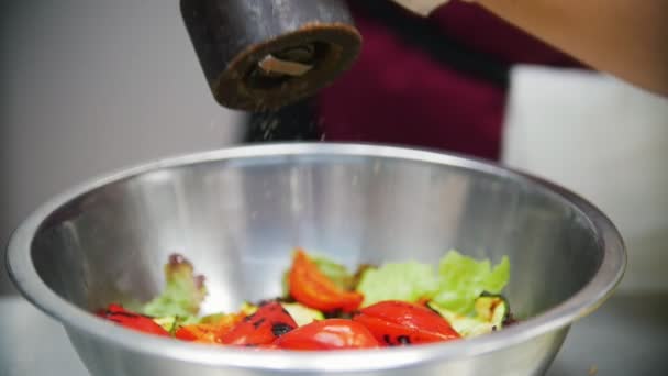 Cook voegt specerijen aan groenten in een kom, in het kader van de hand van de chef-koks — Stockvideo
