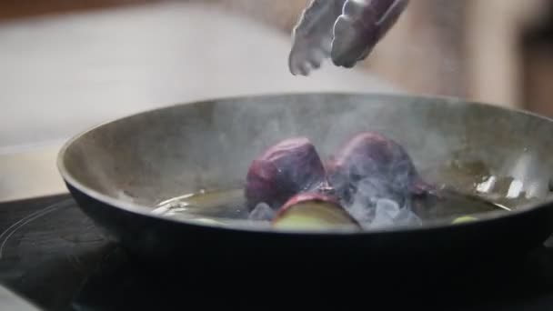 Cocine rodajas de cebolla frita en una sartén con fórceps, en el marco de la mano — Vídeo de stock