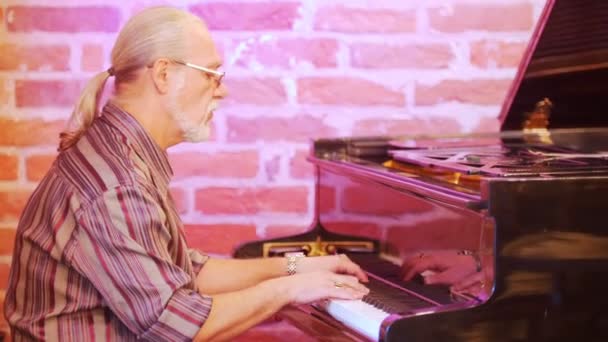 Man musician playing the piano. Hes wearing a plaid shirt, glasses, a gold watch, rings. Gray hair. — Stock Video