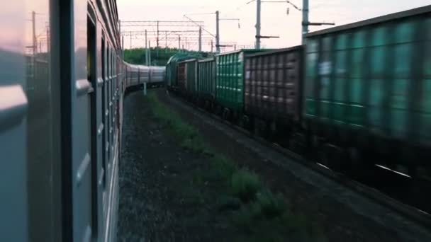 Fotograferen vanuit een rijdende trein. In de tegenovergestelde richting op de aangrenzende spoorwegen passerende goederentrein. — Stockvideo