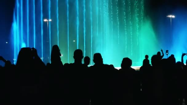 Silhouetten van mensen die genieten van de prachtige paarse fontein en schieten op smartphones op moment van de nacht — Stockvideo