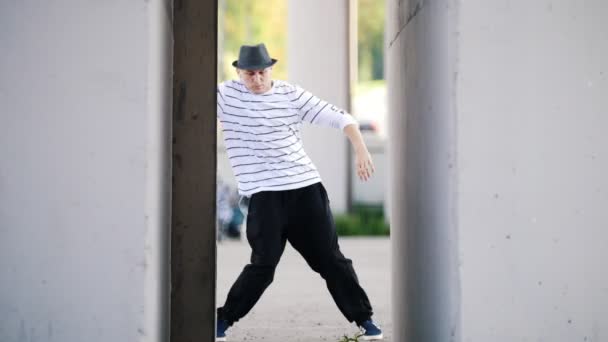 Молода танцівниця переходить до музики в навушниках на вулиці посеред двох стін — стокове відео