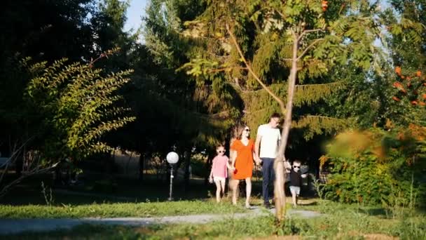 Famille heureuse : papa, maman, fille et fils se promènent dans le parc par une journée d'été ensoleillée — Video