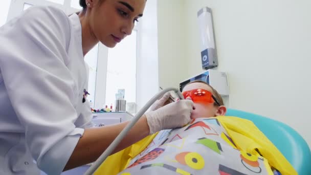 Jovem dentista sensível e cuidadosamente tratar os dentes de um menino — Vídeo de Stock