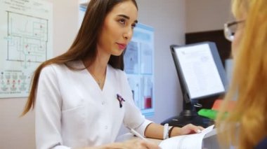 Genç kız dişçi bir kadın hastaya konuşuyor. Kabul edilmek için klinik doktor. Diş Hekimliği.