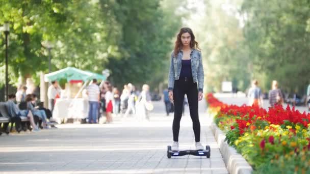 Giovane bella ragazza cavalca un giroscopio nel parco in una giornata estiva — Video Stock