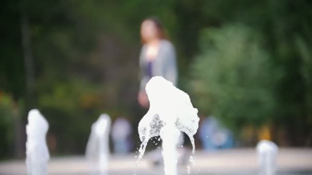 Schöne schlanke Mädchen mit langen Haaren reitet einen Kreisel an den Brunnen, Defokussierung — Stockvideo