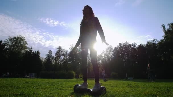 Slanke meisje een gyro rijden op het gras. Shes cirkelen. De zon schijnt. — Stockvideo