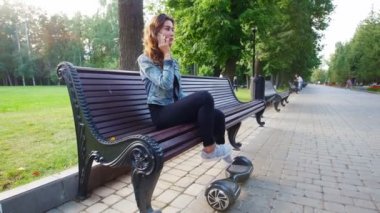 Bir bankta oturan ve telefonda konuşurken ince kız. Sonra bir gyro bankta üzerinden kalkar ve parkta rides.