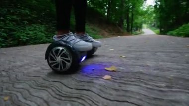 Bayan spor ayakkabı bacaklarda çerçevede. Kız bir gyro Park ormanda sürme.