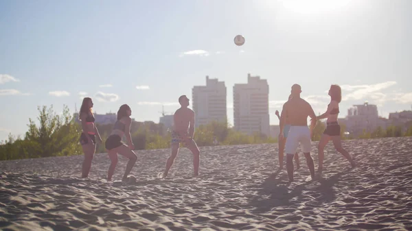 Grupa przyjaciół, gry w siatkówkę na plaży przed piękny zachód słońca — Zdjęcie stockowe