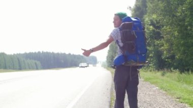 Bir büyük sırt çantası honking ve yol boyunca gider kamera ile genç bir adam