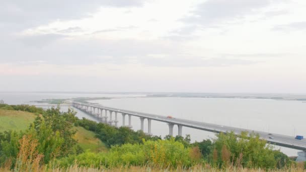 Na velký most přes širokou řeku jezdit auta, šedá obloha — Stock video