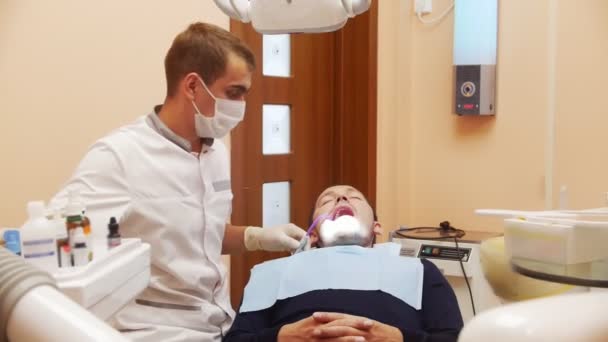 El proceso del dentista. En la recepción en el dentista paciente masculino varón . — Vídeo de stock