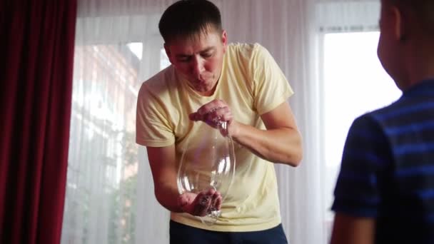 Un uomo organizza uno spettacolo di bolle di sapone a una festa per bambini. In primo piano c'è un bambino . — Video Stock