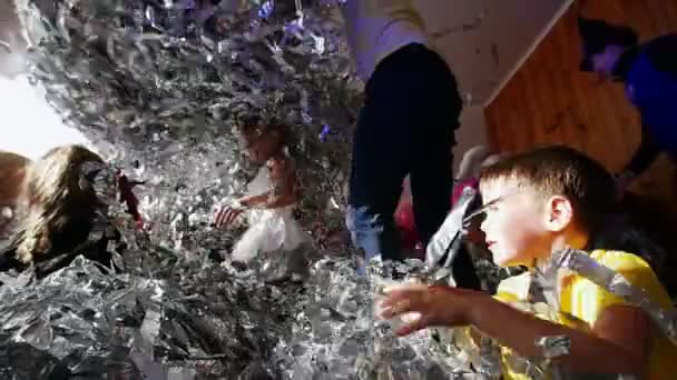 Los niños se divierten nadando en papel de aluminio. Animadores de espectáculos. Una fiesta de niños . — Vídeos de Stock