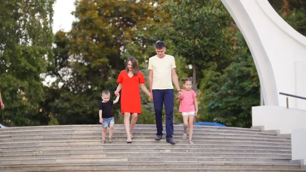 Jong gezin van vier: vader, moeder, dochter en zoon naar beneden de trap in het park, praten — Stockfoto