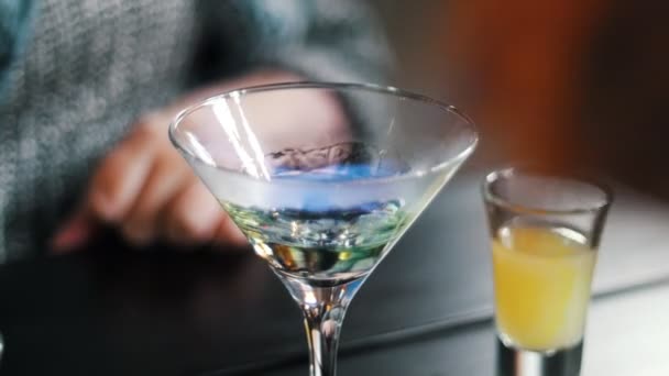 El camarero prende fuego a los cócteles, prepara bebidas alcohólicas, el camarero prepara bebidas con fuego junto al mostrador del bar — Vídeo de stock