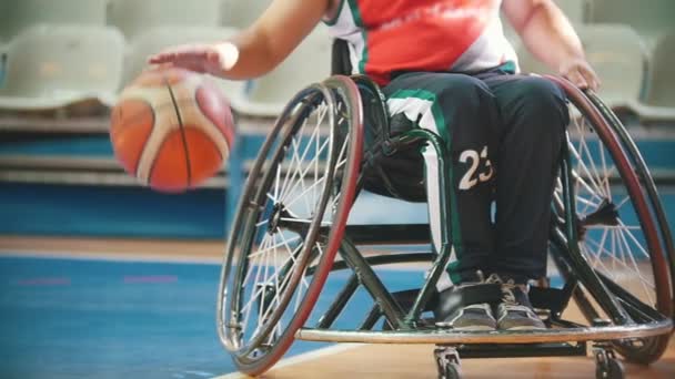 Cadeira de rodas com deficiência, prática de jogador de basquete jogando com a bola tha no salão de esporte — Vídeo de Stock